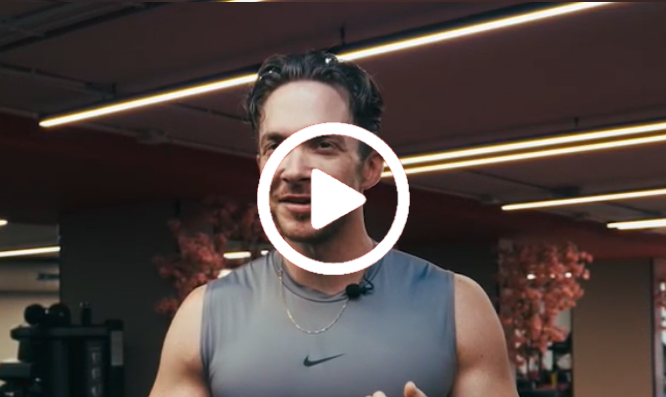 Vrouw in een sportschool met fitnessapparaten en neonverlichting aan het plafond, met daarop een afspeelknop.