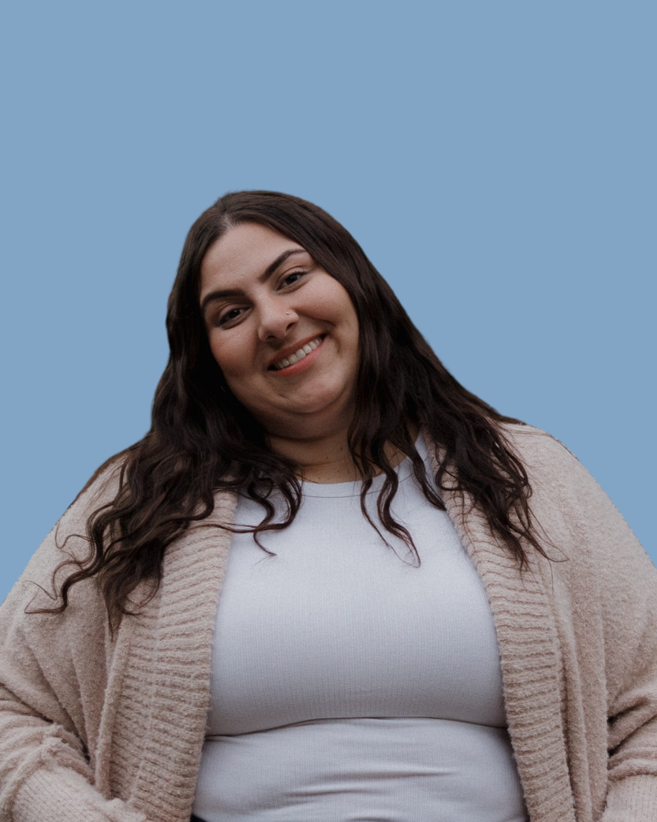 Smiling person with long dark hair in a black shirt against a teal background
