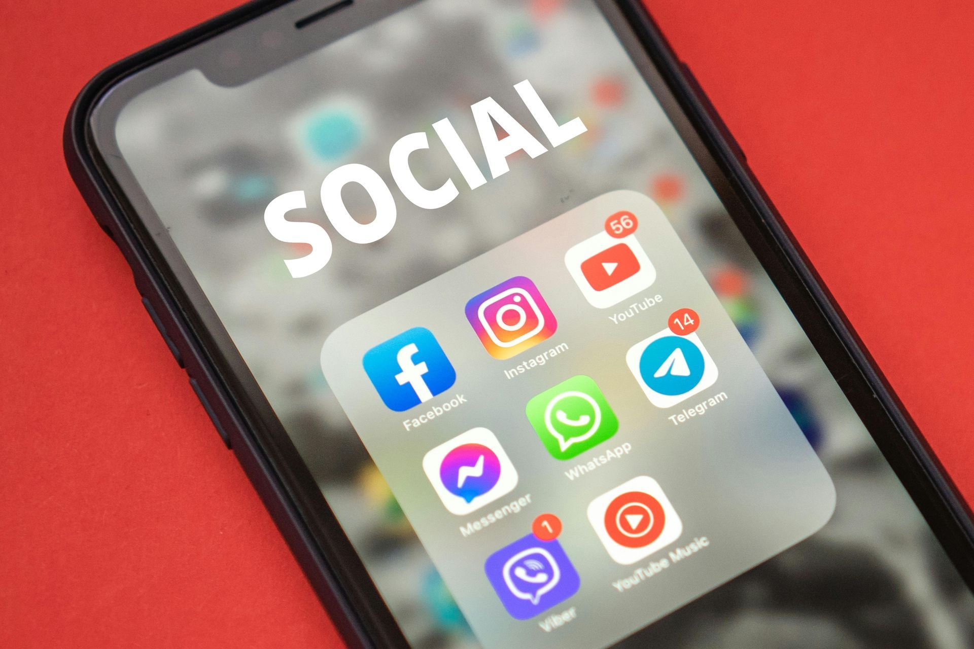 A smartphone screen against a red background displays a folder titled SOCIAL containing various social media app icons.