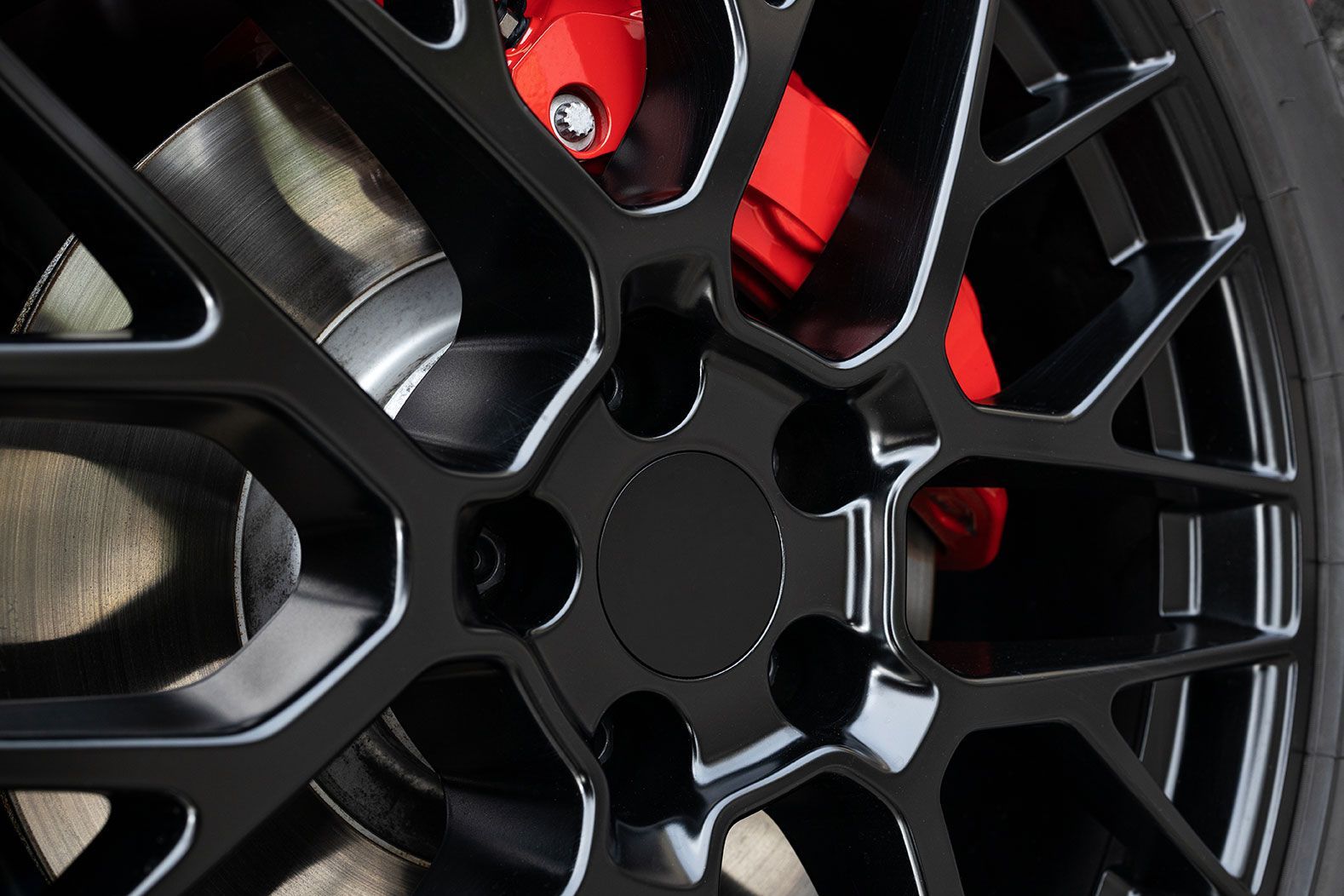 Close-up of a black alloy car wheel with red brake caliper details