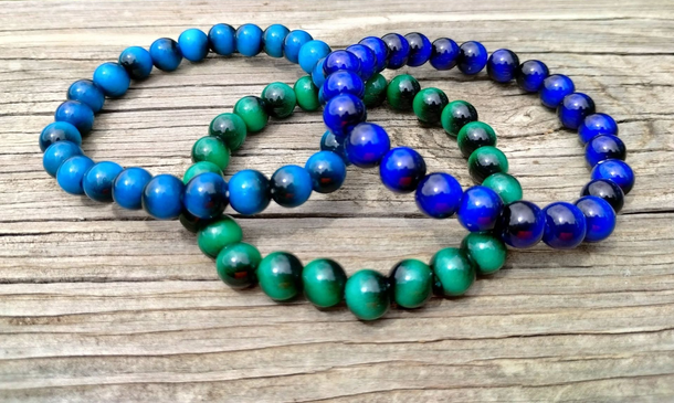 Beaded bracelets in blue, green, and purple on wood with “New Arrivals” banner
