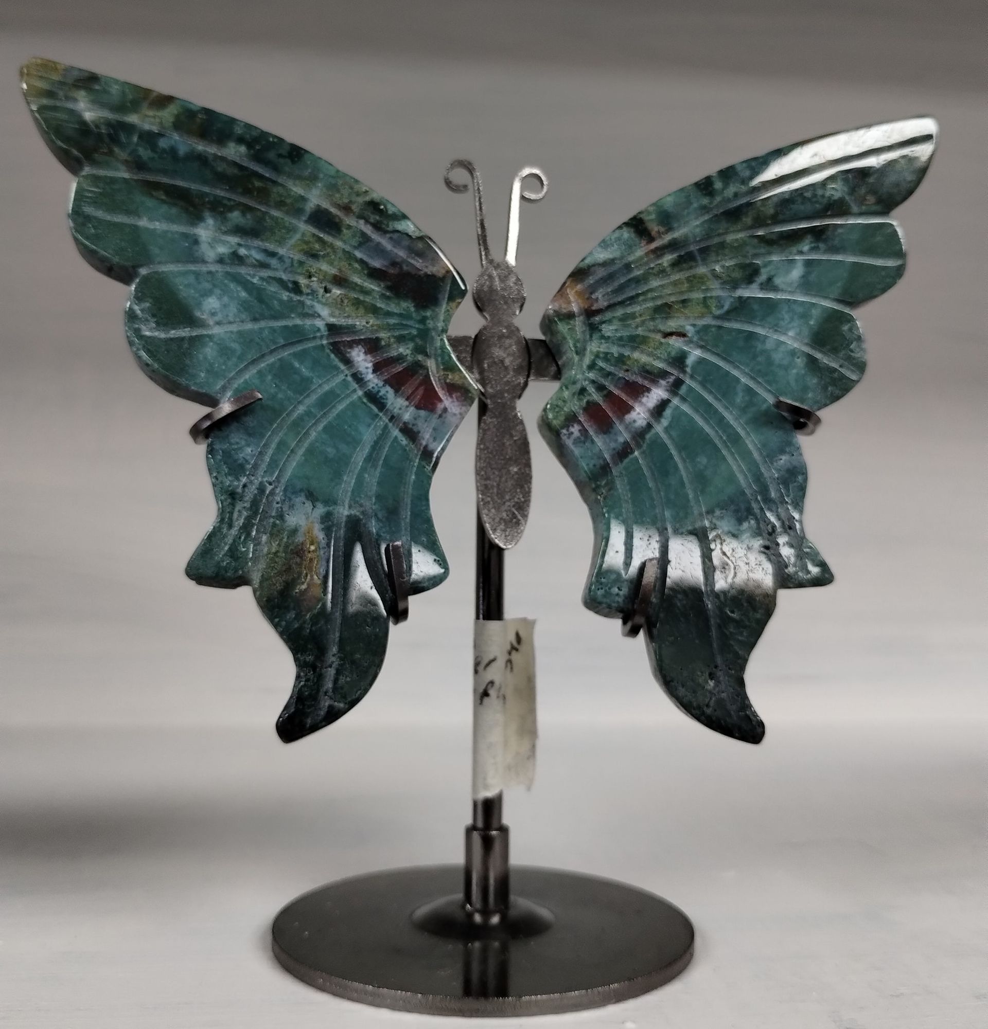 Green stone butterfly sculpture on a metal stand.