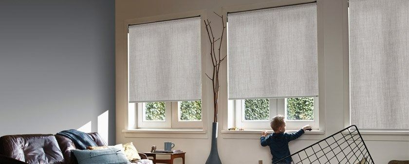 A Little Boy is Looking Out of a Window in a Living Room — Simply Smarter Blinds in Corlette, NSW