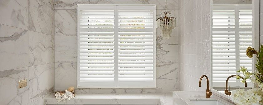 A Bathroom With a Tub and Window With White Shutters — Simply Smarter Blinds in Medowie, NSW