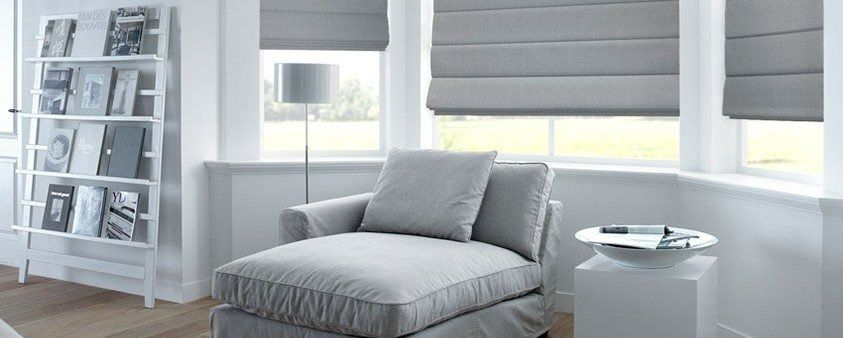 A Living Room With a Chair, Ottoman, Bookshelf and Roman Blinds — Simply Smarter Blinds in Nelson Bay, NSW