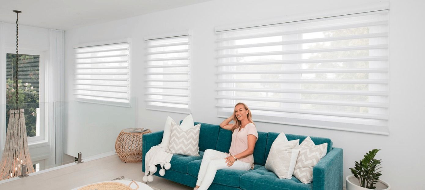 A Woman is Sitting on a Blue Couch in a Living Room — Simply Smarter Blinds in Tea Gardens, NSW