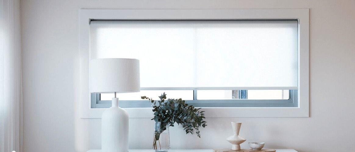 A Lamp is Sitting on a Table in Front of a Window — Simply Smarter Blinds in Tea Gardens, NSW