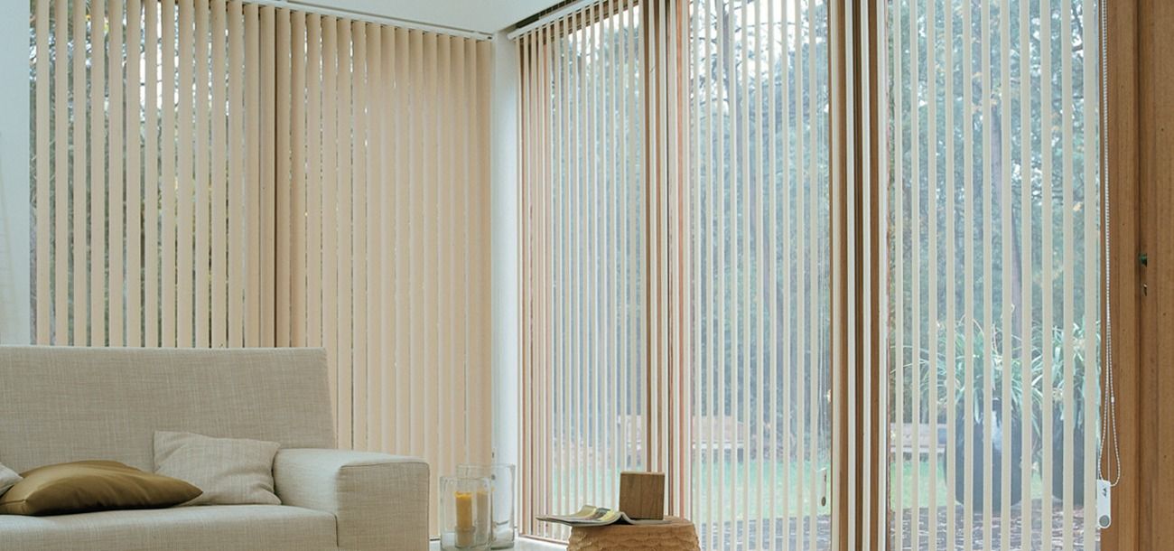 A Living Room With a Couch and a Lot of Windows With Vertical Blinds — Simply Smarter Blinds in Tea Gardens, NSW