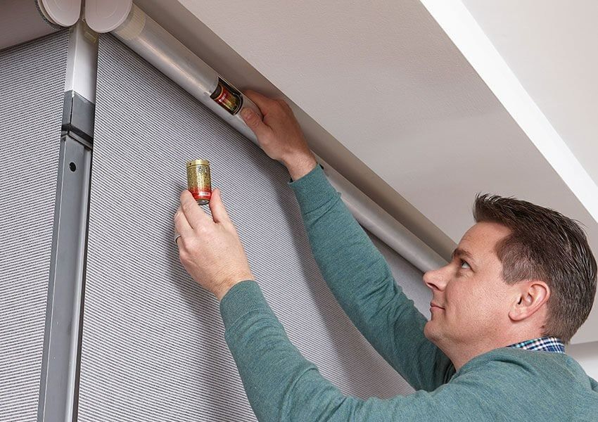 A Man in a Green Sweater is Measuring a Wall With a Tape Measure — Simply Smarter Blinds in Soldiers Point, NSW