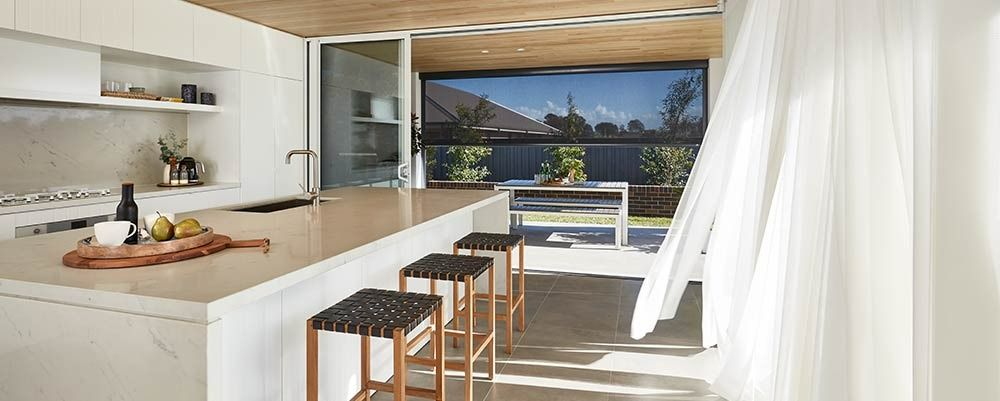 A Kitchen With a Long Island and Stools and a Large Window — Simply Smarter Blinds in Soldiers Point, NSW