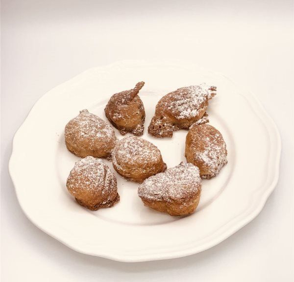 Une assiette blanche garnie de beignets recouverts de sucre en poudre