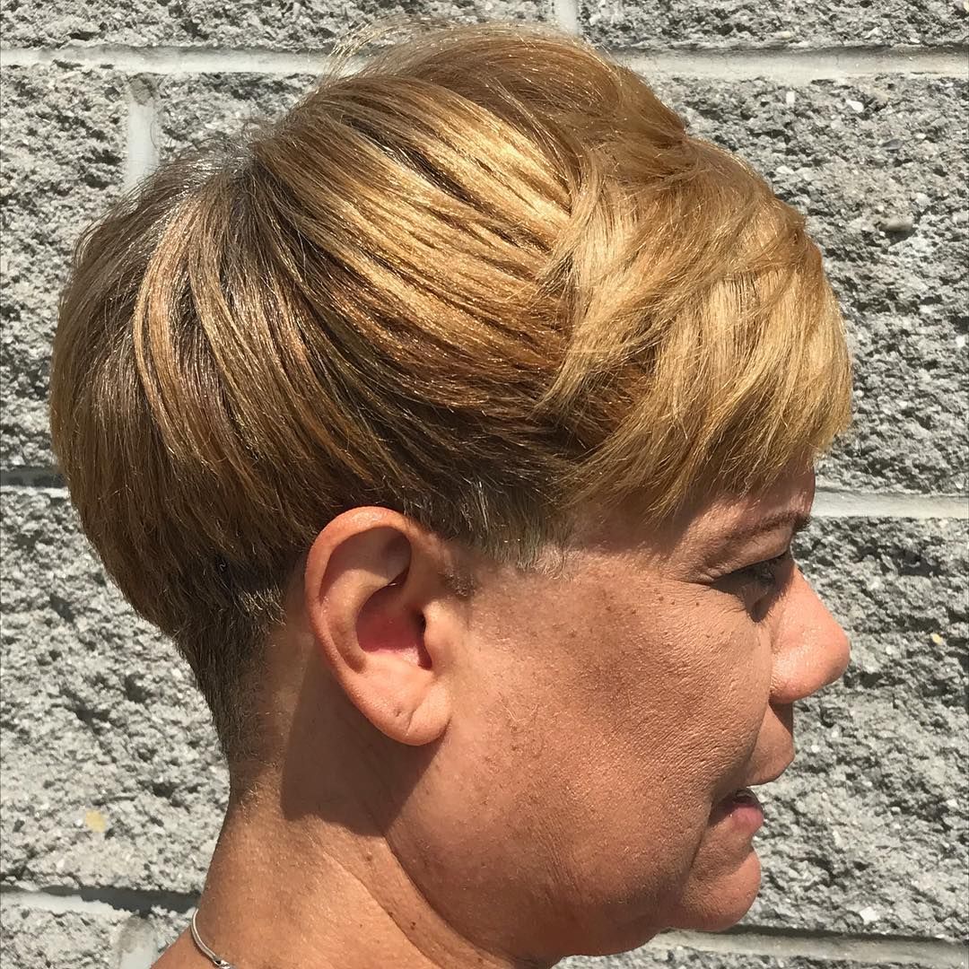 Profile view of a person with short blond hair against a stone wall