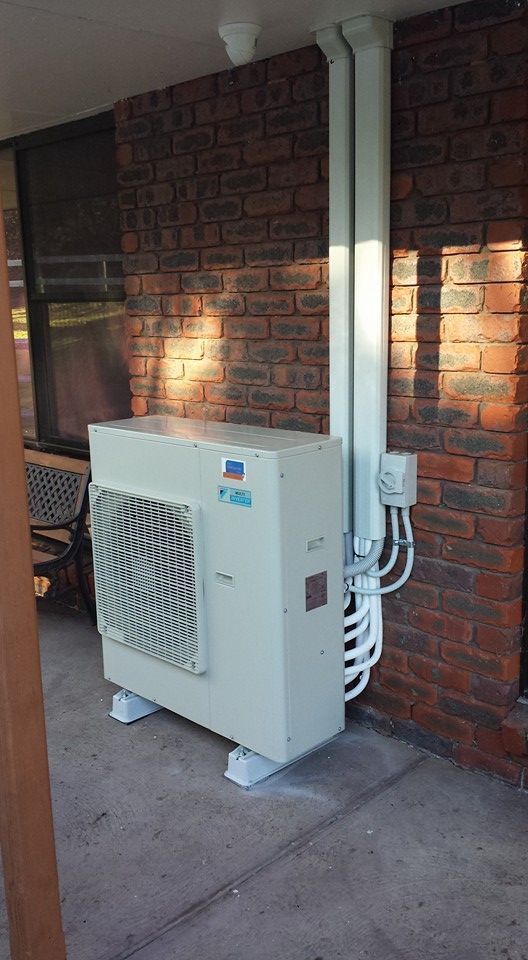 A White Air Conditioner Is Sitting on The Side of A Brick House- Hobart, TAS - The Heat Pump Man