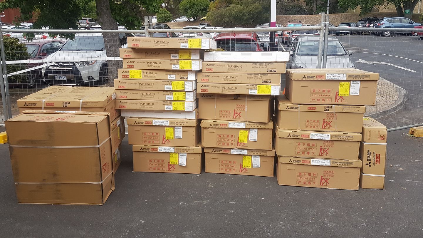 A Bunch of Cardboard Boxes Are Stacked on Top of Each Other in A Parking Lot- Hobart, TAS - The Heat Pump Man