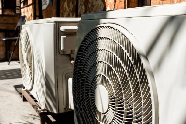 Two Air Conditioners Are Sitting Next to Each Other Outside of A Building- Hobart, TAS - The Heat Pump Man
