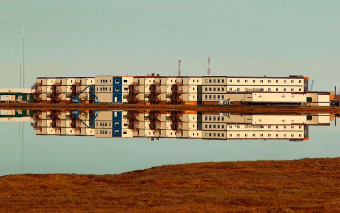 A large building is reflected in a body of water.