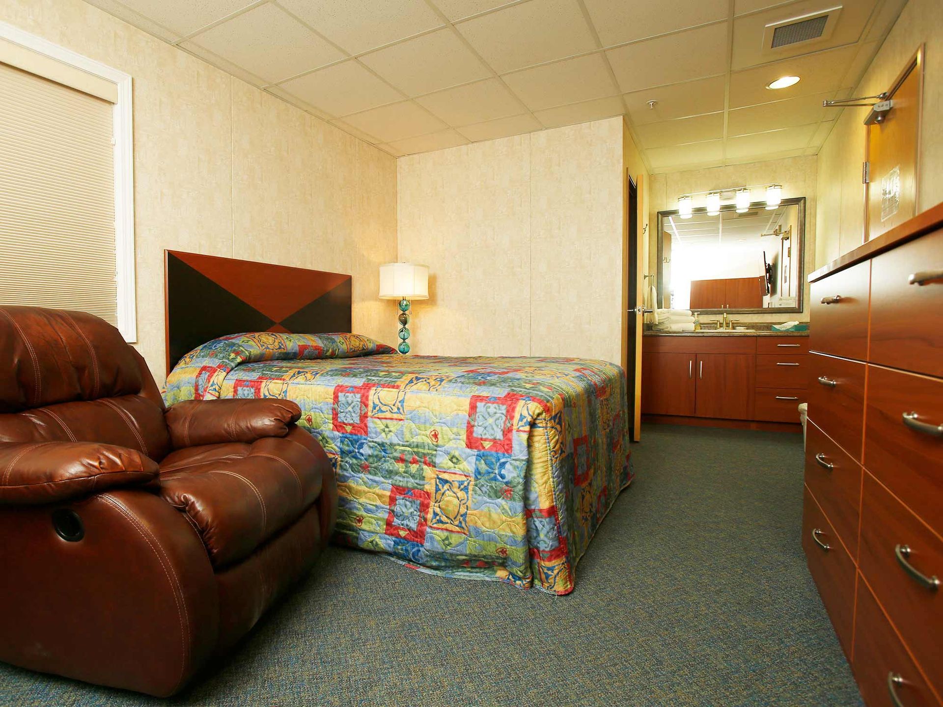 A hotel room with a recliner and a bed