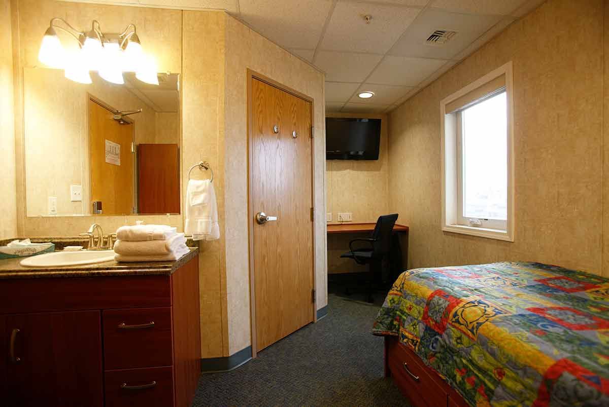 A hotel room with a bed , sink , mirror and television.