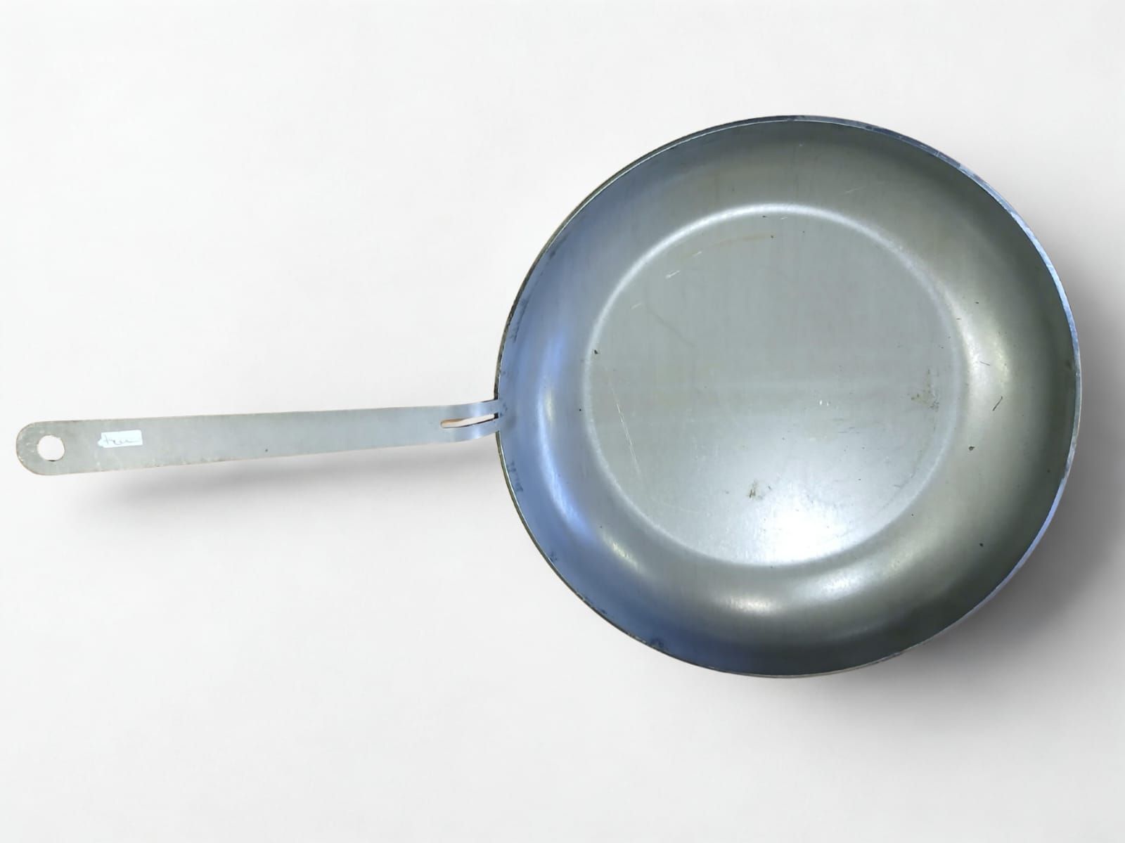 Sartén de plata sobre superficie blanca.