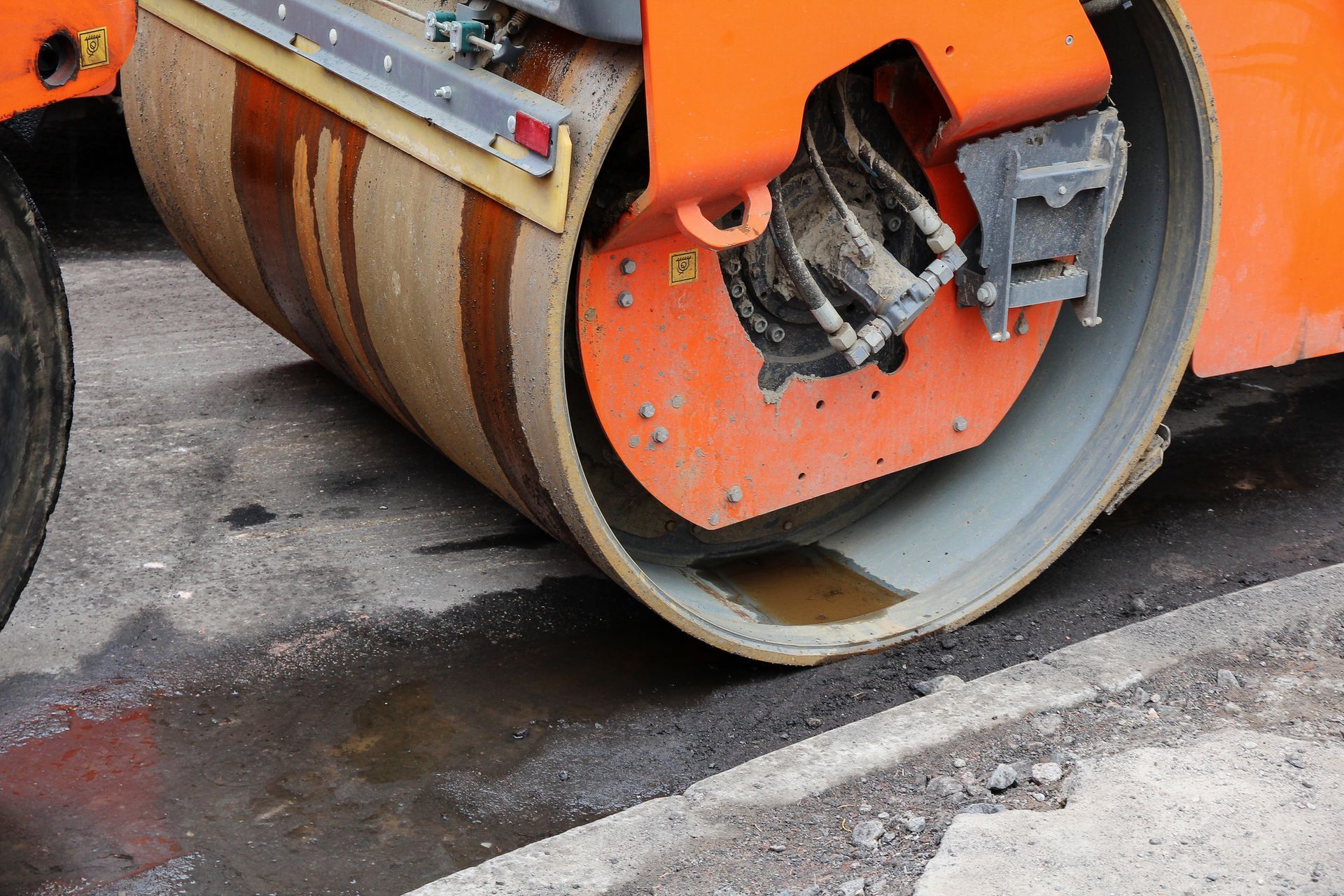A close up of an orange roller on a road