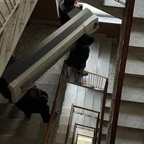 Persone che trasportano un grande divano lungo una stretta tromba delle scale in un edificio.
