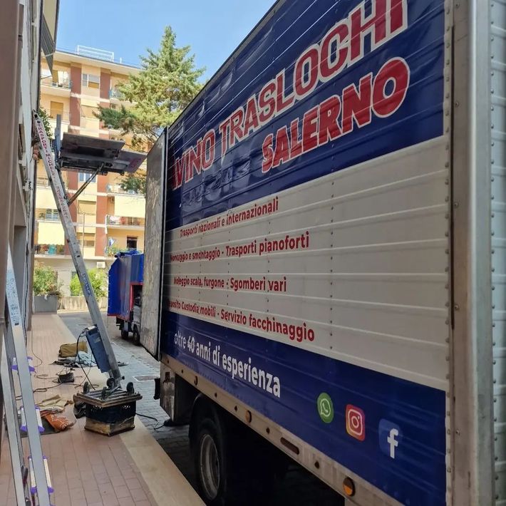 Furgone commerciale parcheggiato in una strada stretta accanto a un condominio, con una scala e degli attrezzi nelle vicinanze.