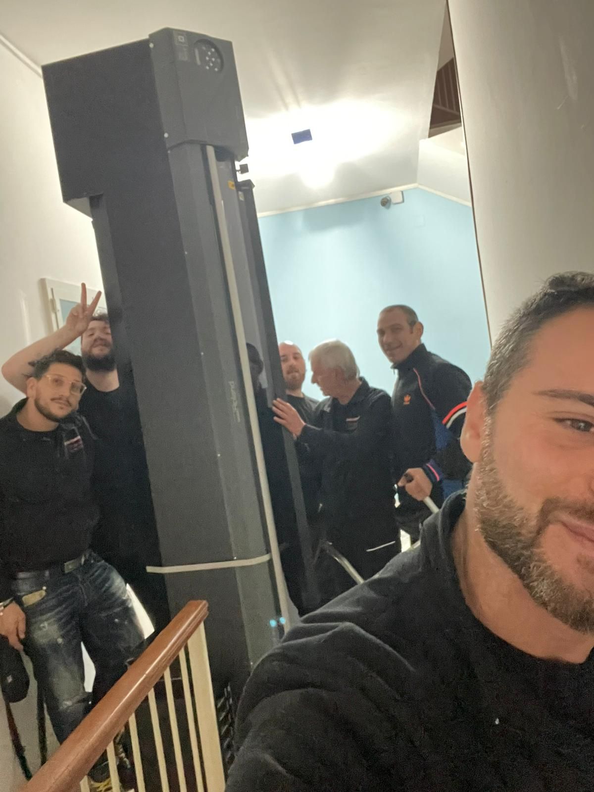 Alcune persone posano su una tromba delle scale, con un uomo che si scatta un selfie in primo piano.