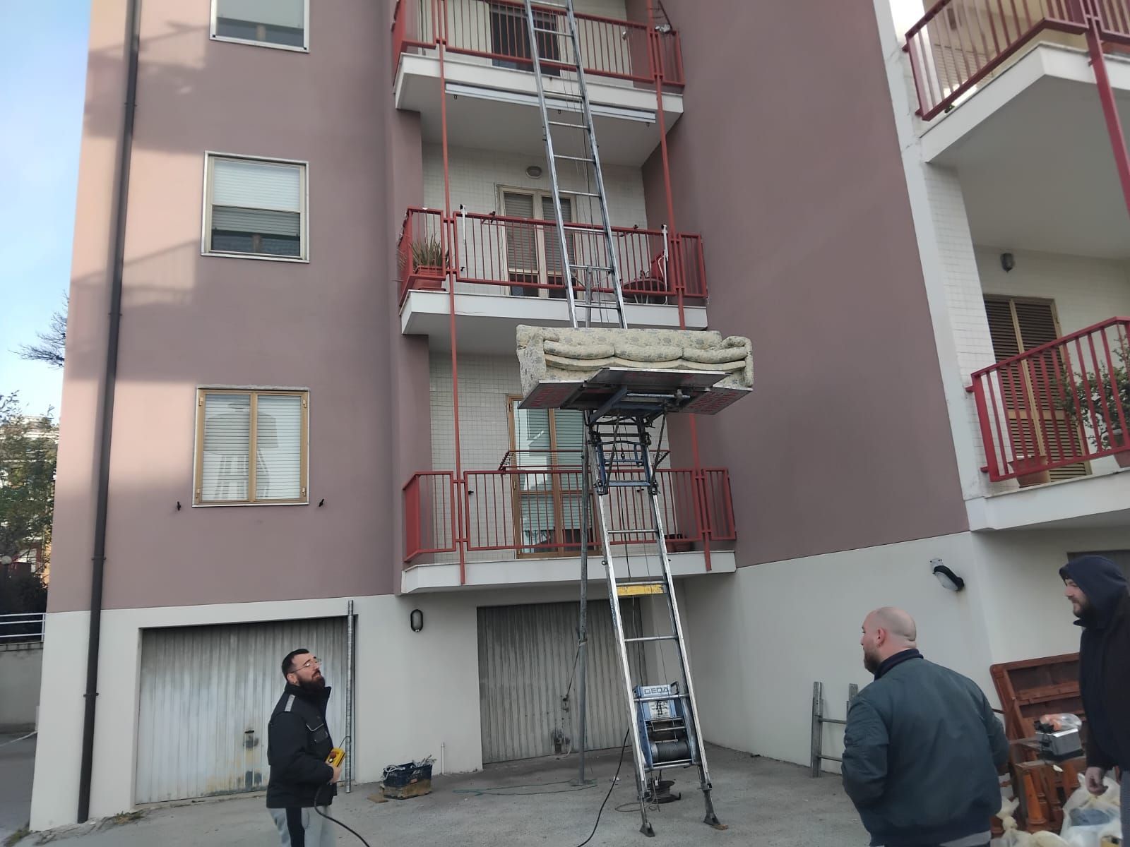 Operai su una scala e un'impalcatura riparano la facciata e i balconi di un condominio.