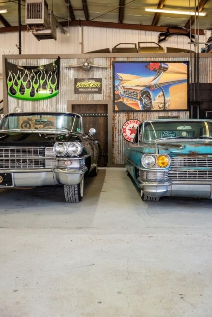Two old cars are parked next to each other in a garage.