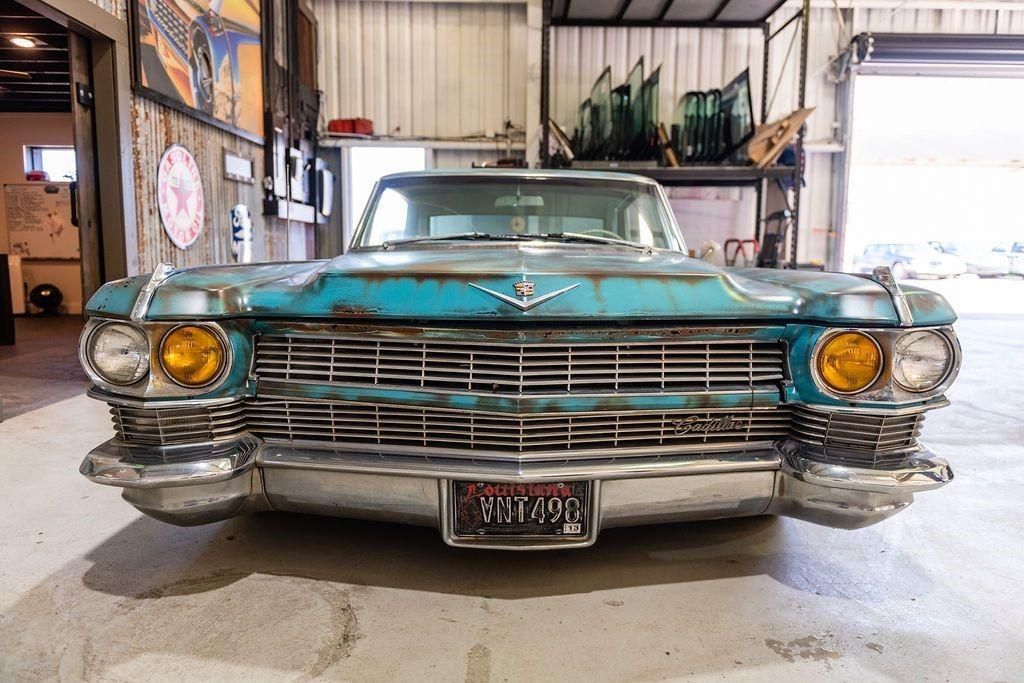 A blue car with a california license plate is parked in a garage.