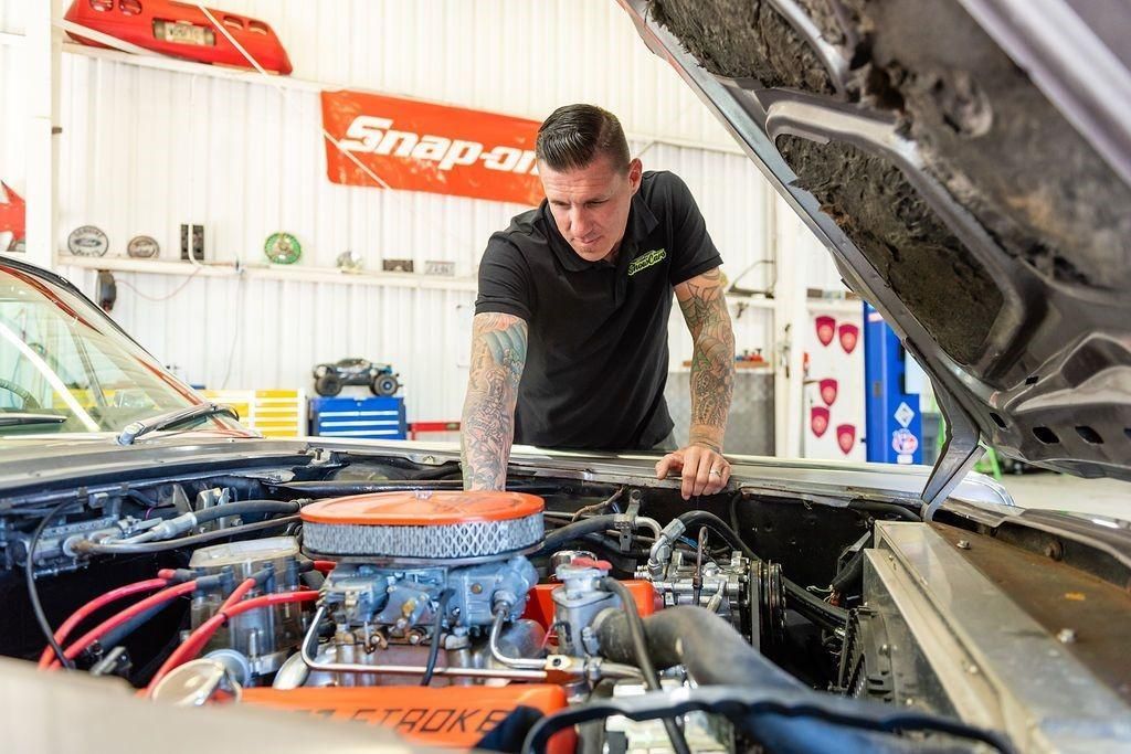 A man is working on the engine of a car in a garage.