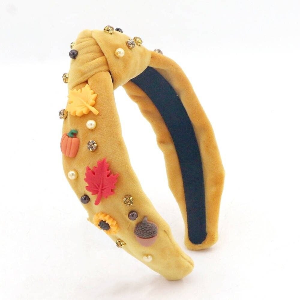 Mustard yellow headband with fall-themed embellishments including a pumpkin, leaves, pearls and jewels.