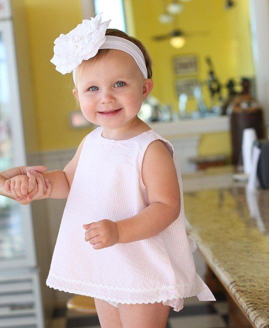 A little girl wearing a pink dress and a white headband