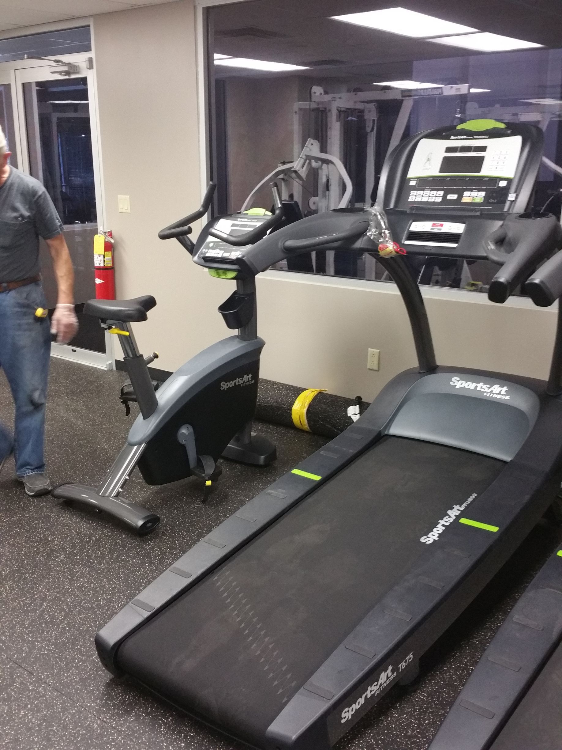 Gym with a treadmill, stationary bike, and other exercise equipment in a workout room.