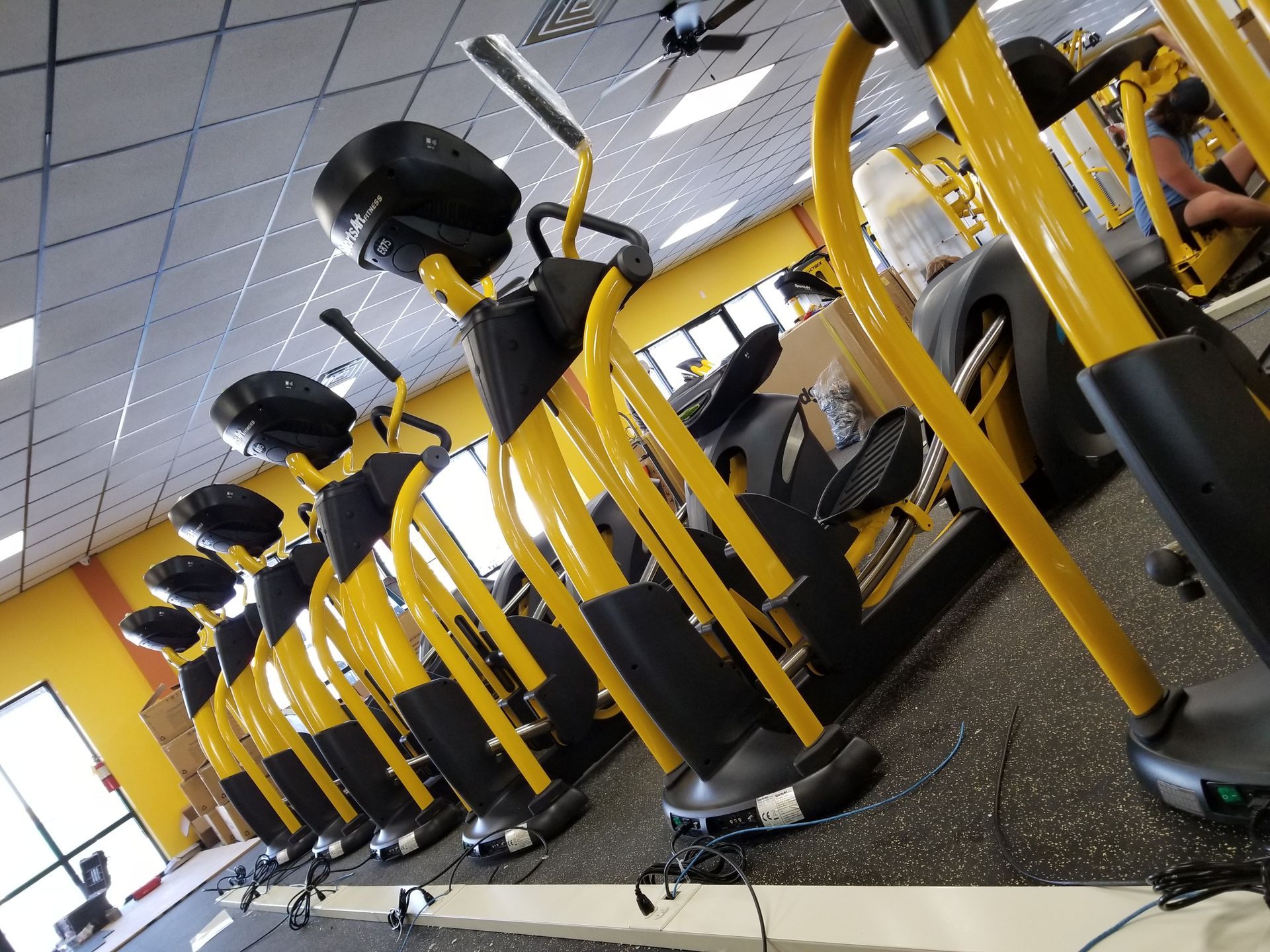 Row of yellow stationary exercise bikes in a gym, viewed at an angle.