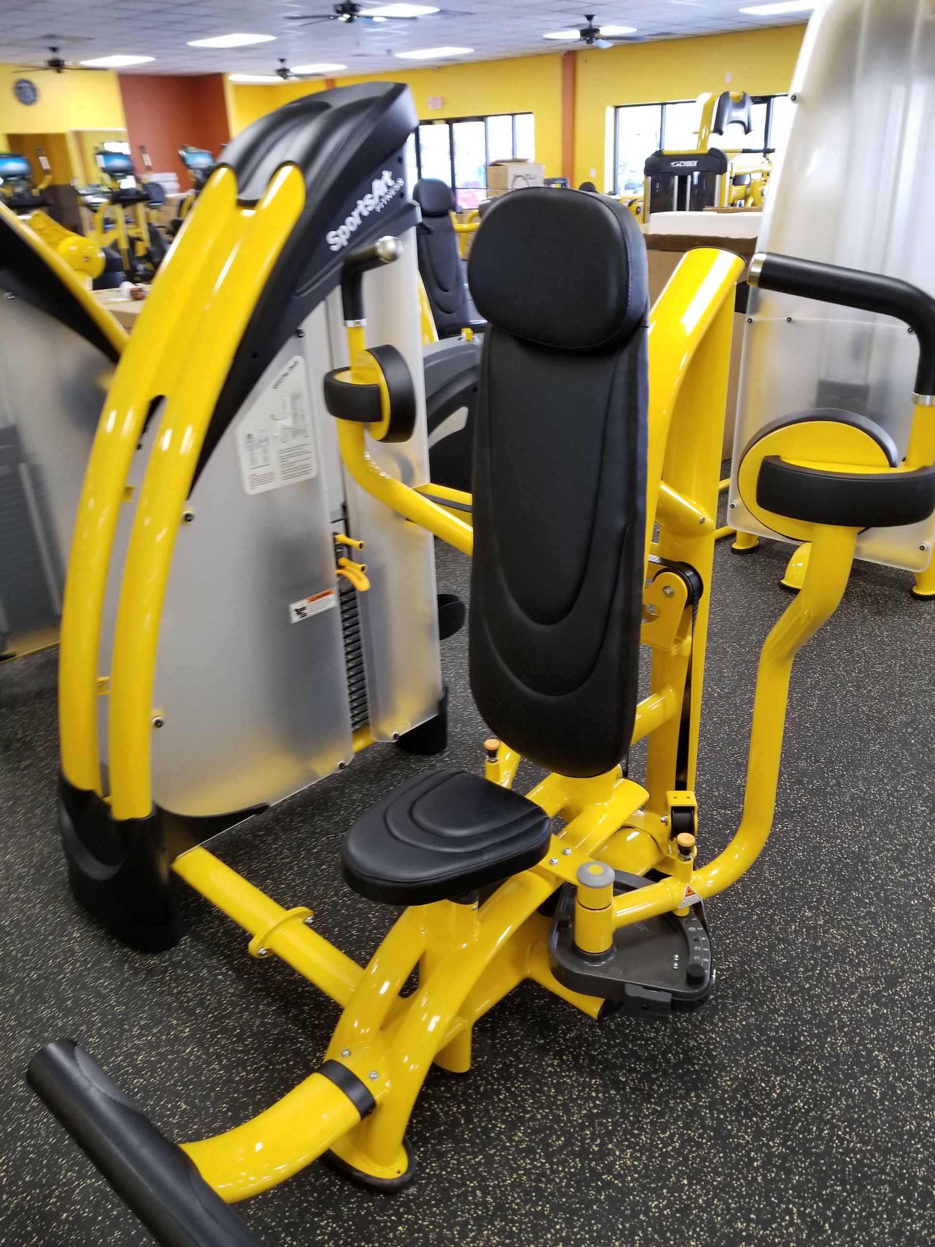 Yellow and black seated gym strength machine in a fitness room