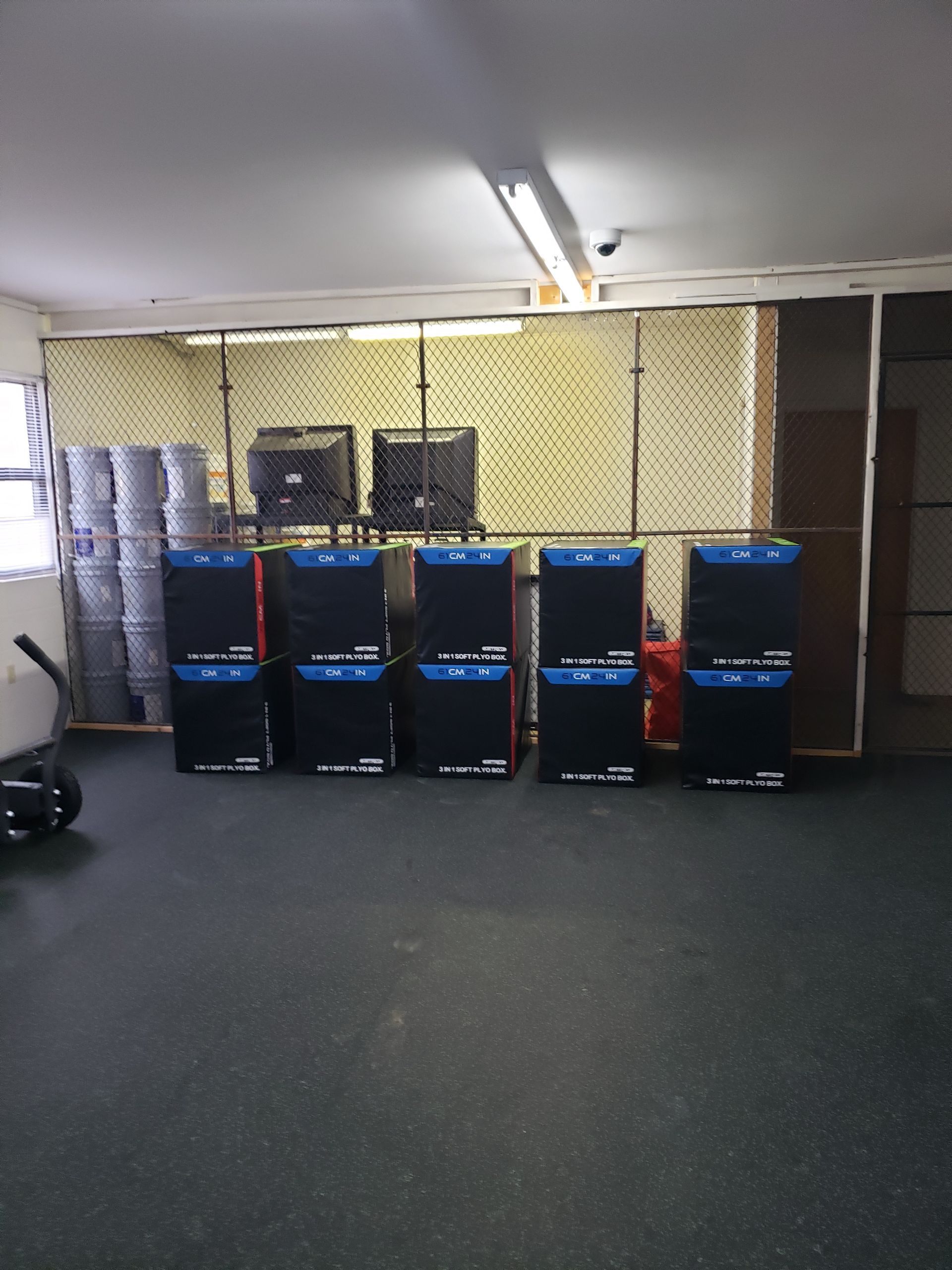 Basement storage room with stacked blue bins, shelves, and fluorescent lighting