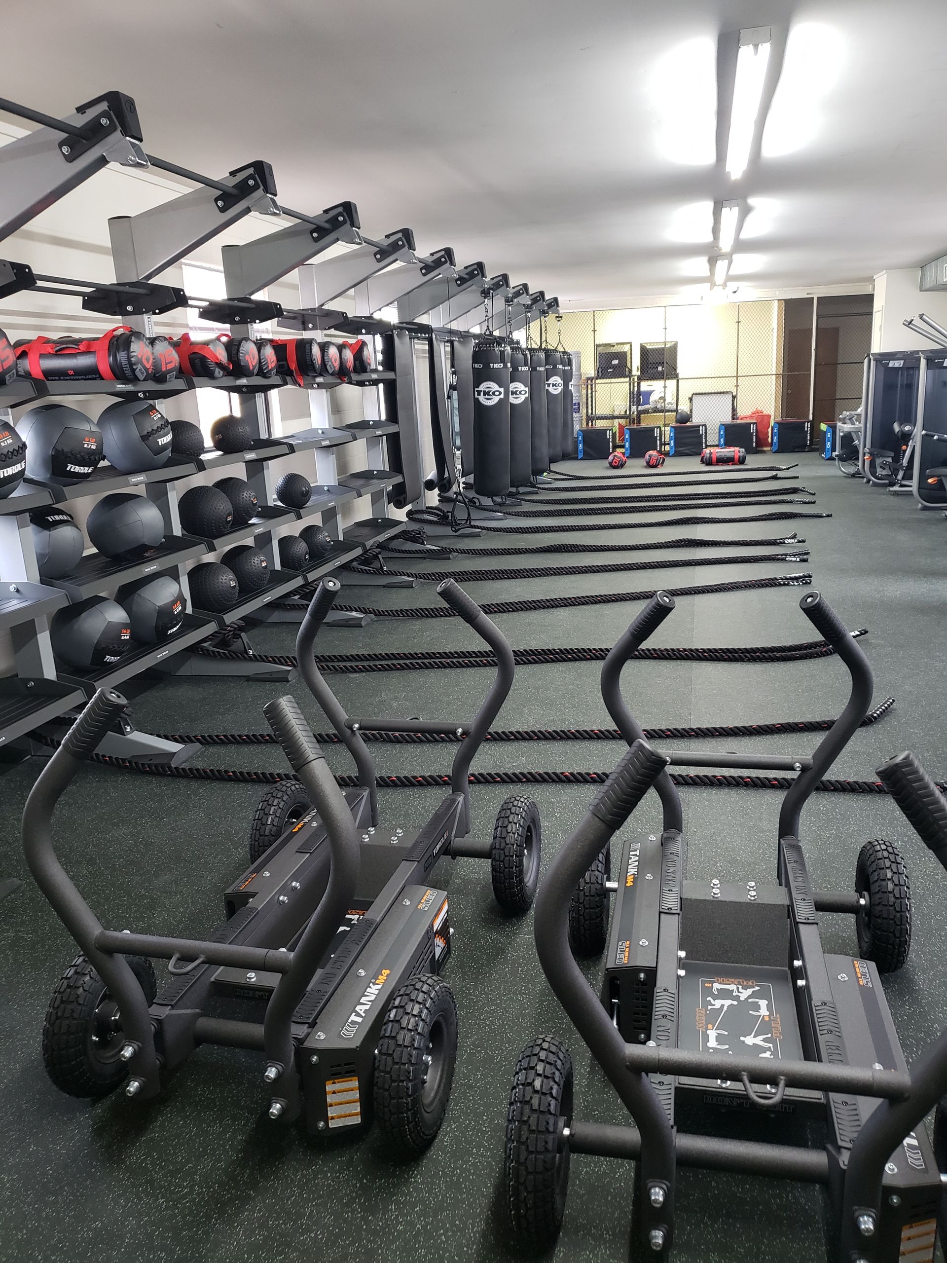 Gym interior with rows of black exercise machines and kettlebells on wall racks