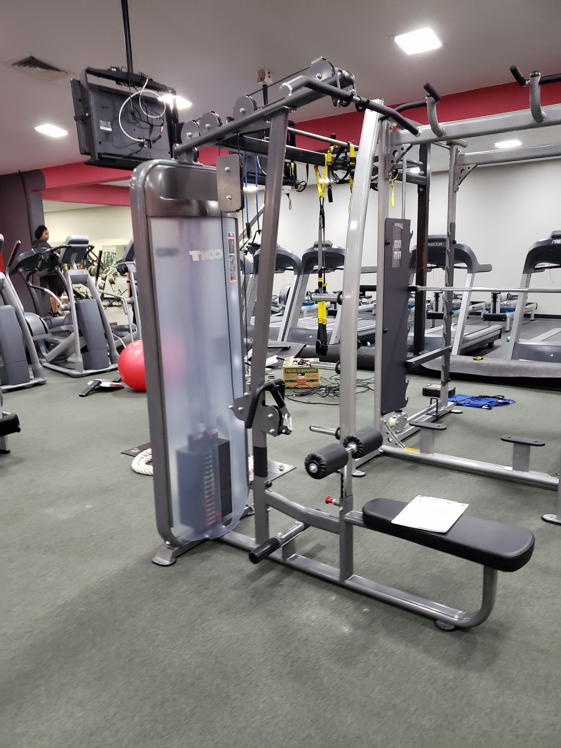 Gym cable machine with gray frame and black seat in a fitness center