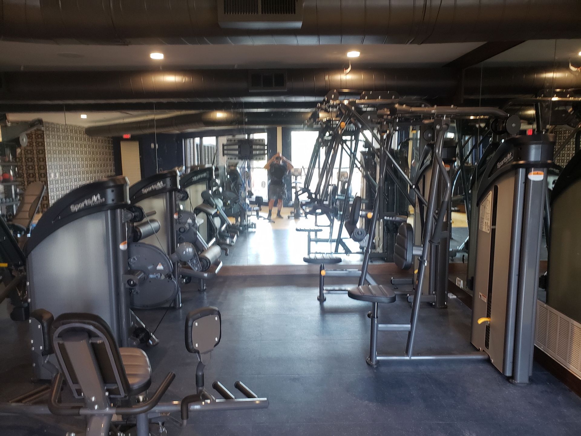 Gym interior with rows of exercise machines and weights in a dimly lit room