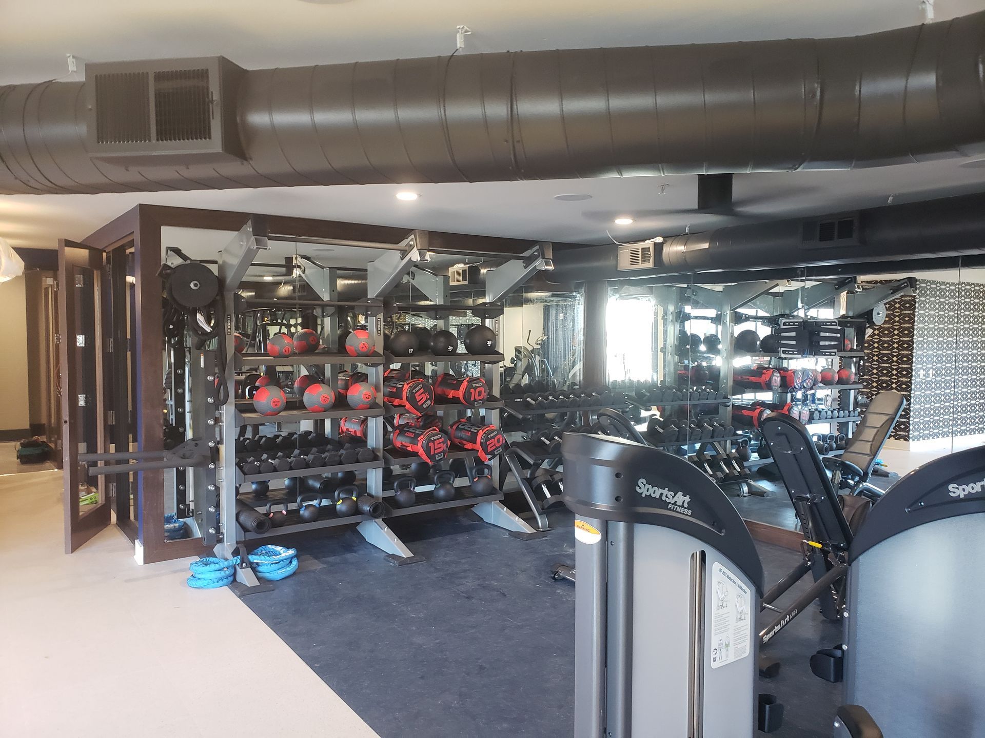 Gym interior with weight racks, exercise machines, and exposed ductwork in a wide open room