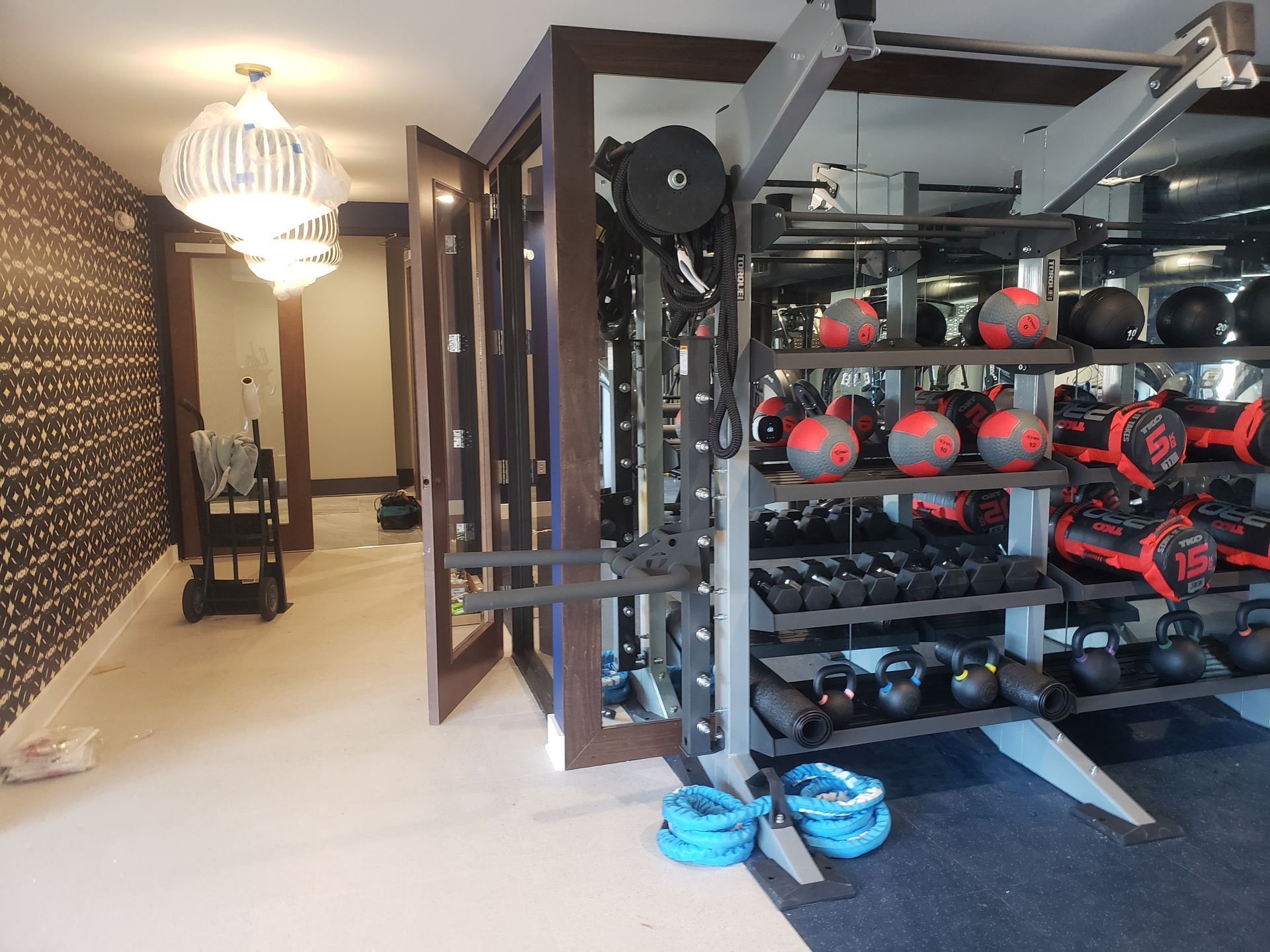 Gym with exercise equipment, dumbbells, medicine balls, and a cable machine in a mirrored room