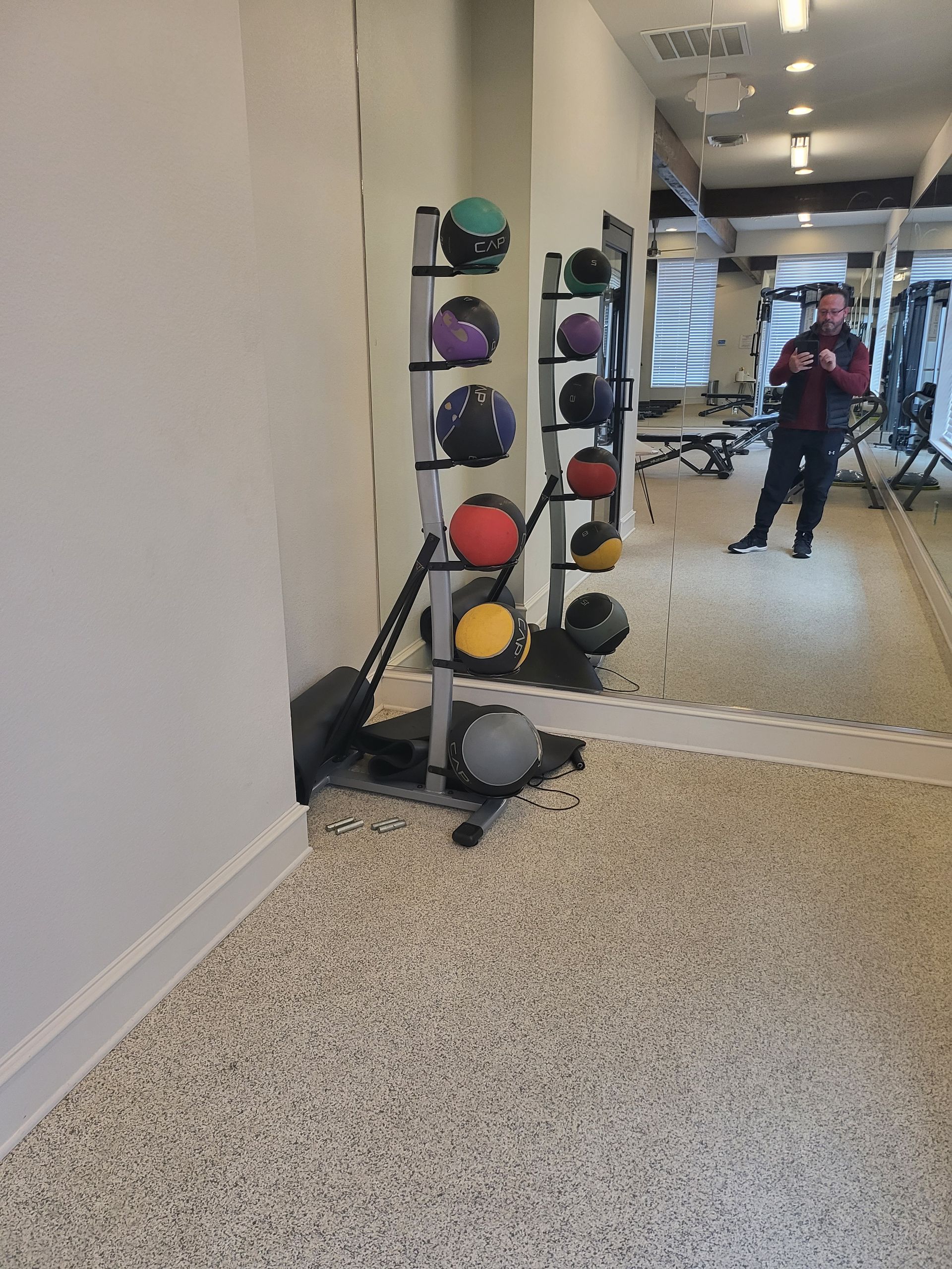 Gym hallway with a rack of colorful medicine balls.