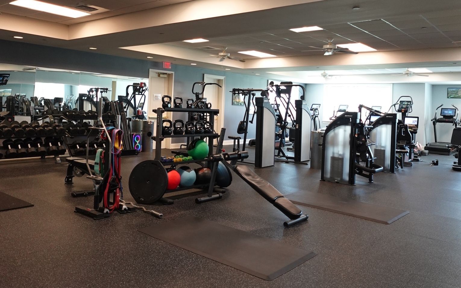 Empty gym with weight machines, benches, and exercise balls.