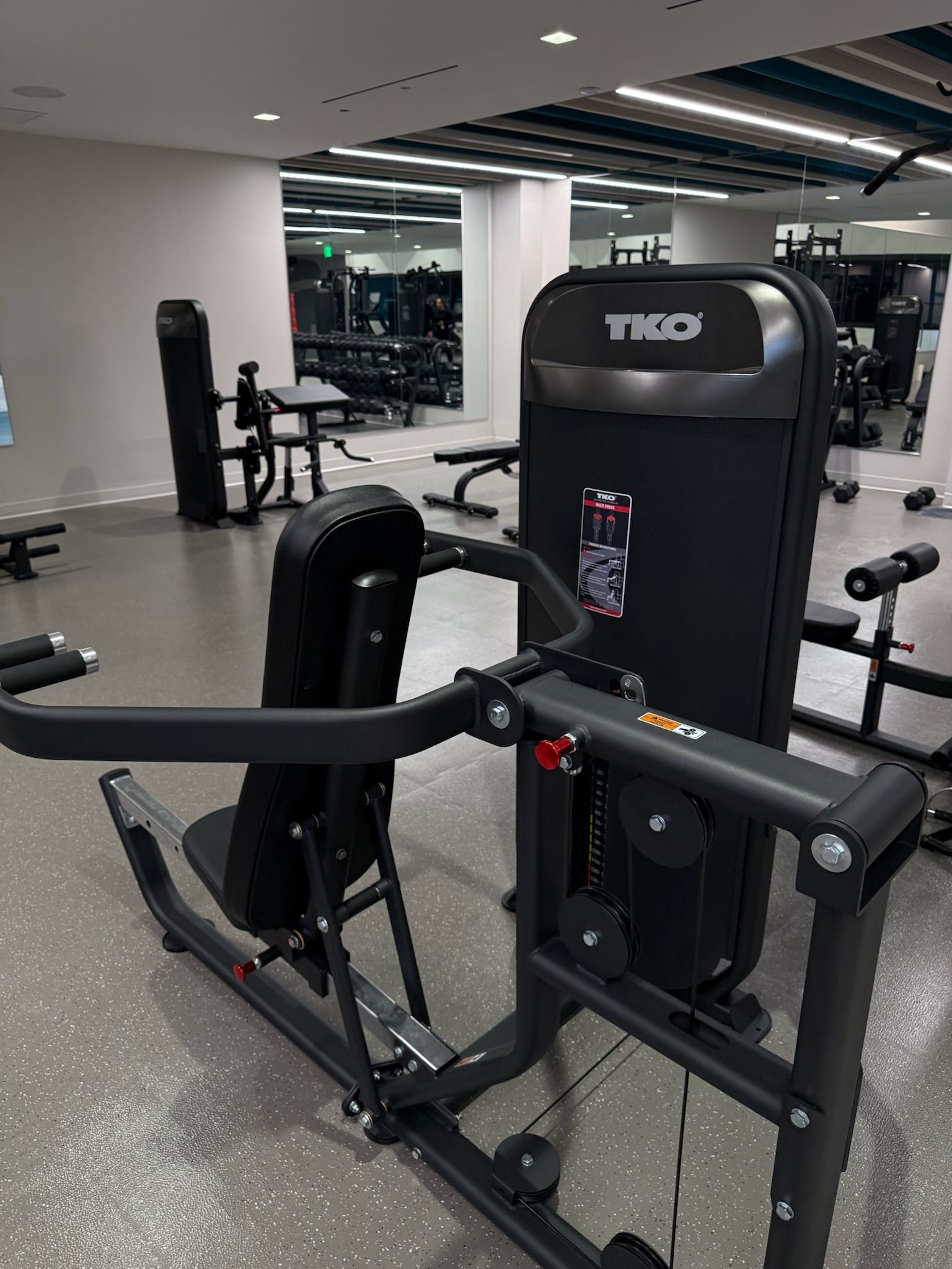 Gym machine in a fitness room with mirrors and gray flooring