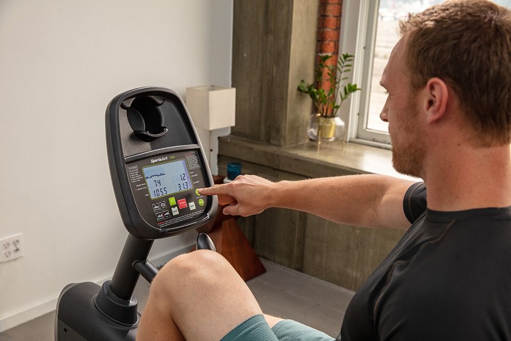 Modern stationary exercise bike  in a bright room with large window and city view