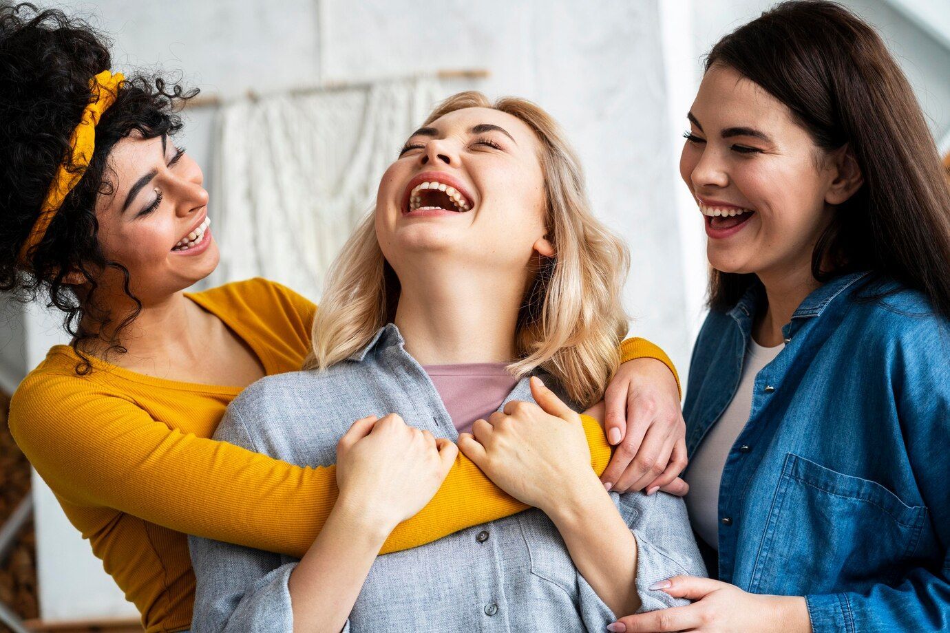 Three women are hugging each other and laughing together.