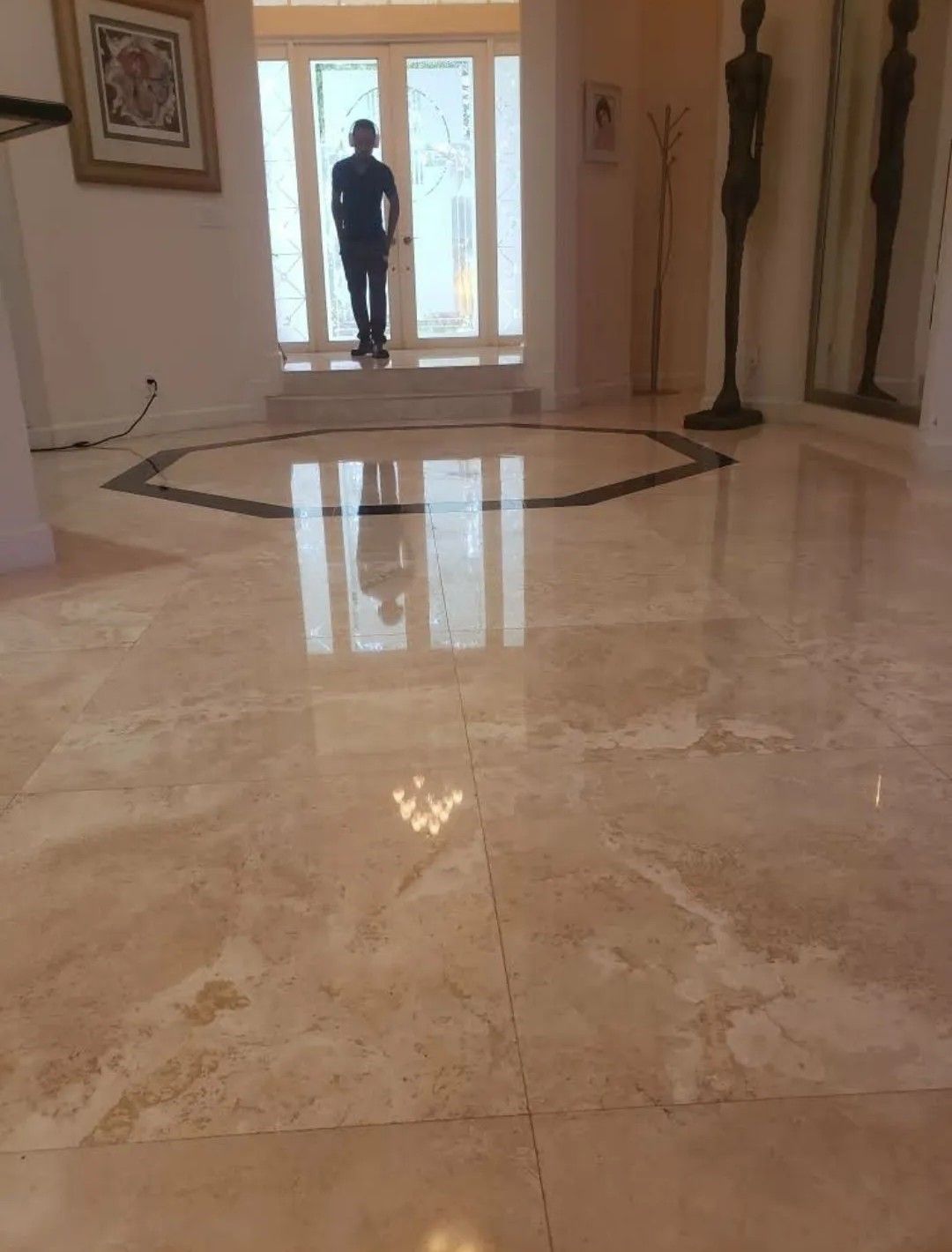 Polished marble foyer with a person silhouetted in the doorway and mirrors along the walls.