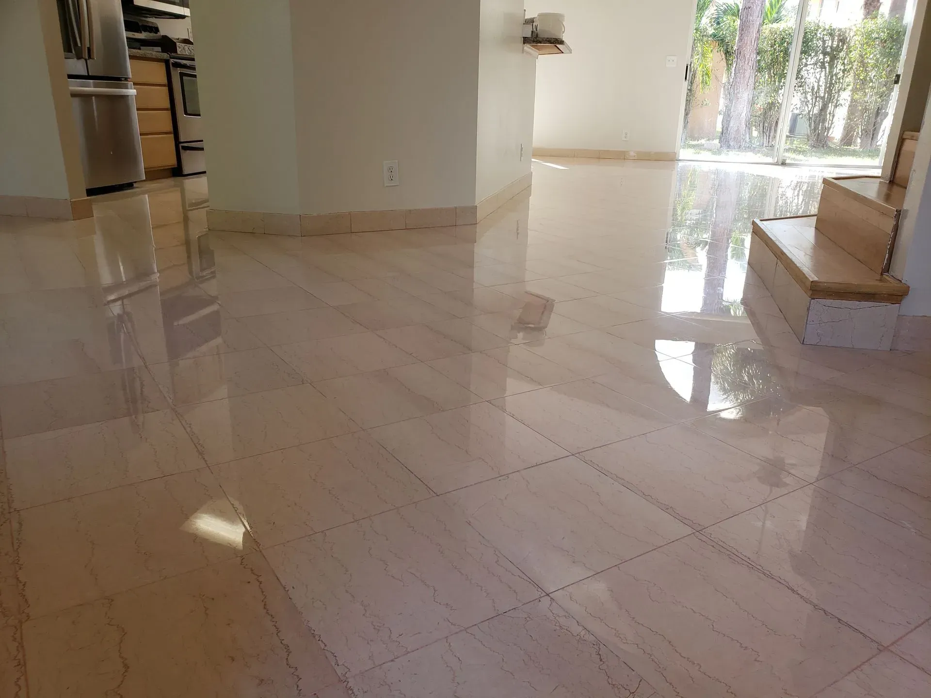 Glossy marble-floored foyer with sunlight reflections and a view of the outdoors through glass doors