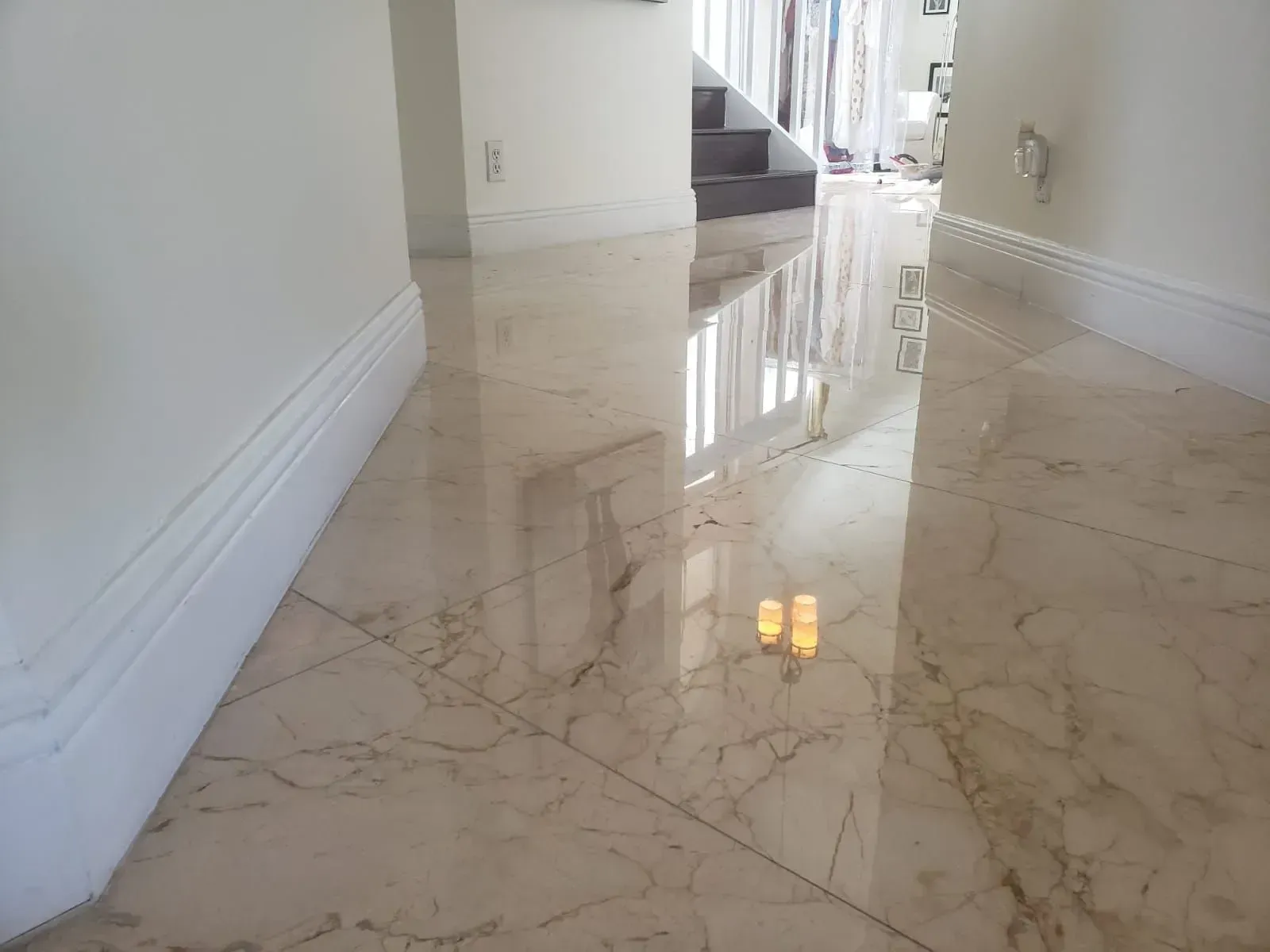 Polished marble hallway with white walls and a staircase reflection on the floor
